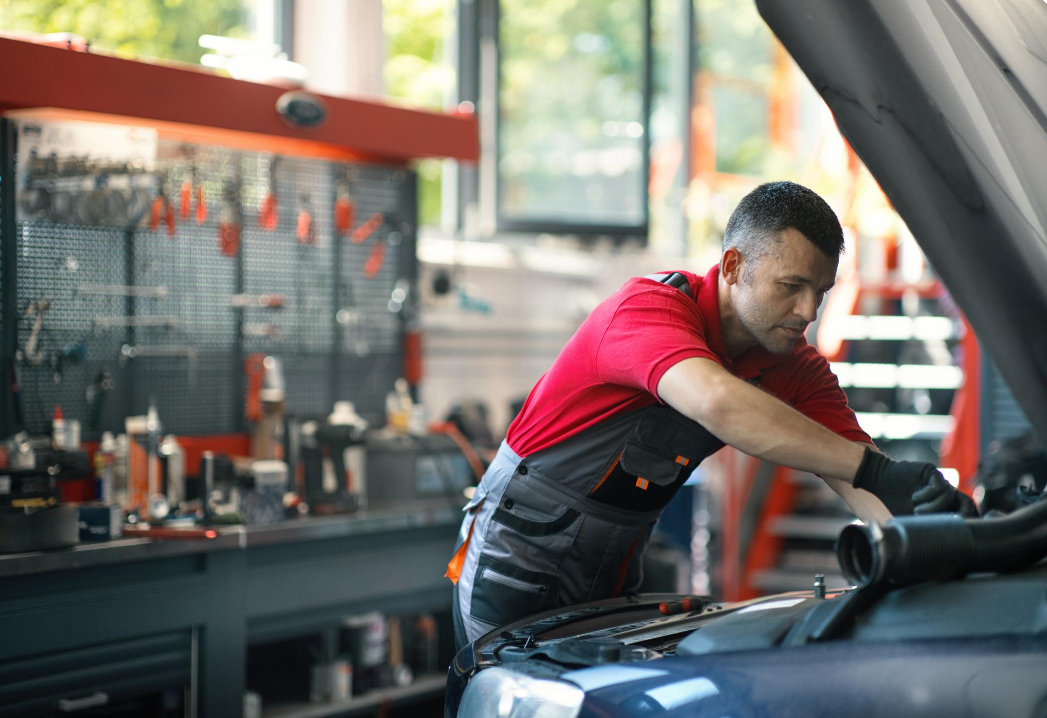 Closeup of a 40's male care mechanic working on an engine at a car repair shop